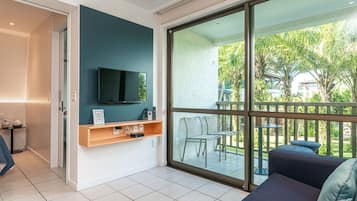Uma sala de estar moderna com televisão de tela plana, sofá e varanda com mobiliário de exterior.