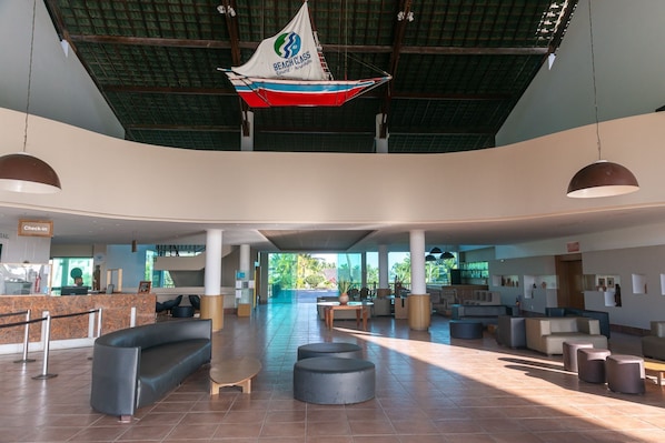 Un vestíbulo amplio con mostrador de recepción, zonas de estar y una gran decoración de un velero.