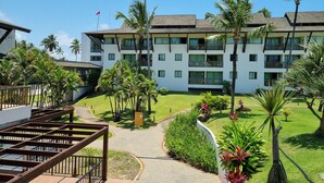 A multi-story hotel with a central courtyard, surrounded by palm trees and a well-maintained lawn. - BeachClass Muro Alto Porto de Galinhas (Ipojuca)