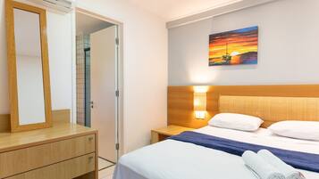 Ein Hotelzimmer mit einem Bett, einem Nachttisch, einer Wandlampe, einem Gemälde und einem Spiegel.