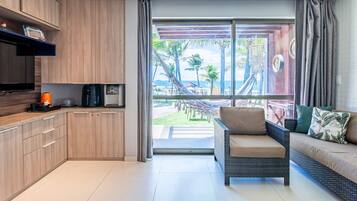 A modern kitchen with a large sliding glass door leading to a balcony with a view of palm trees and the sea.
