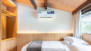 Een hotelkamer met een bed, een wandairconditioner en een raam met gordijnen.