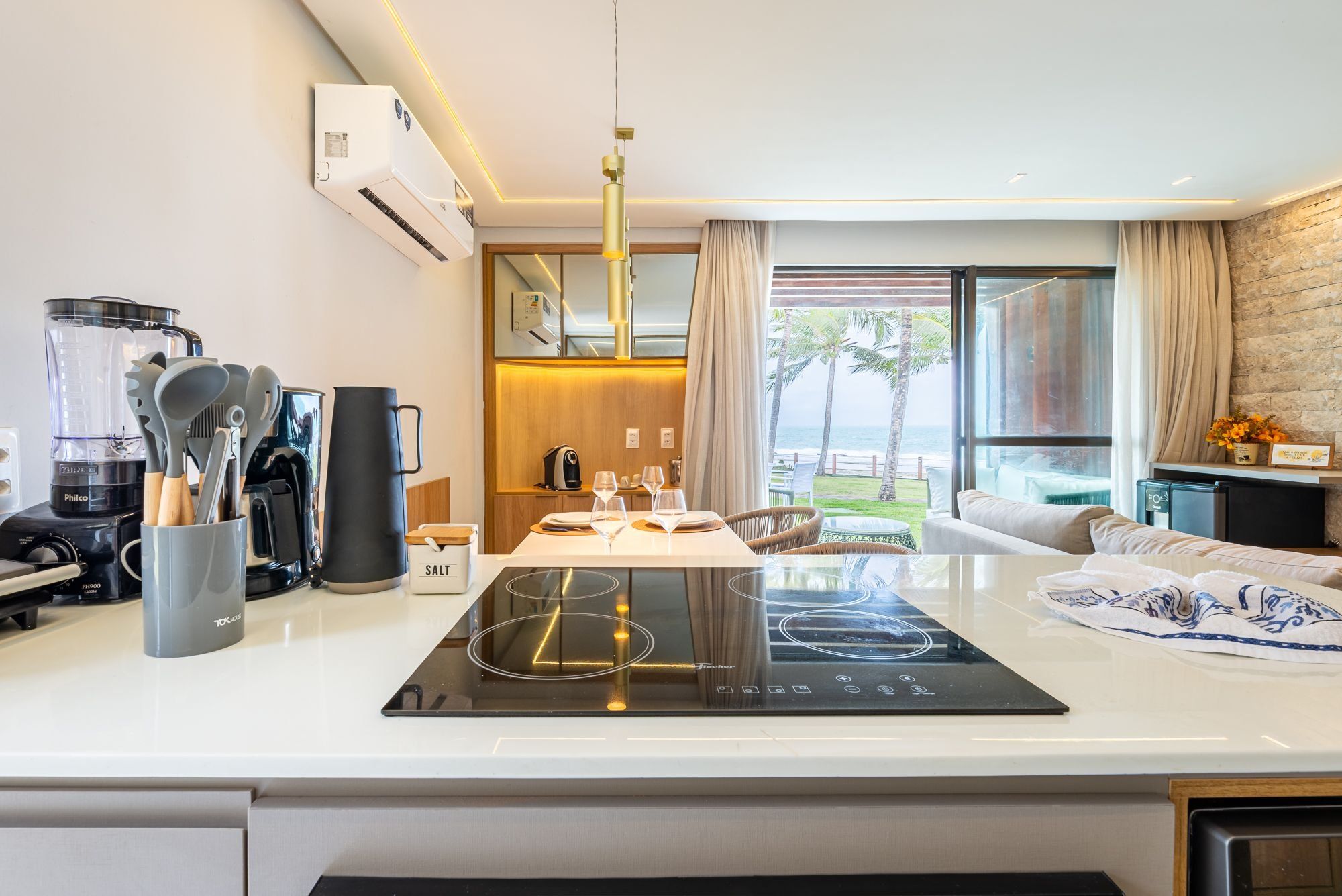 A modern kitchen with a built-in induction cooktop, a blender, and a coffee maker.