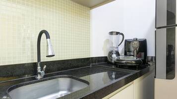 A kitchen with a stainless steel sink, a coffee maker, and a blender on the counter.