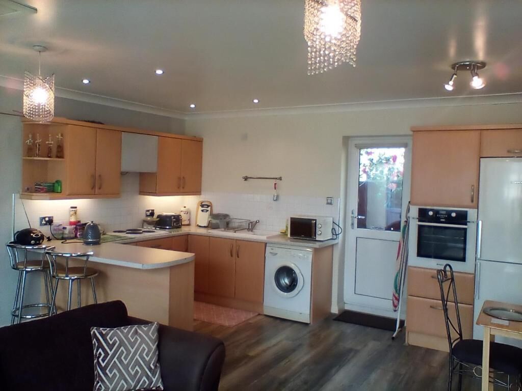 A compact kitchen with a washing machine, microwave, and a small dining area.