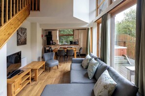 Ein modernes Interieur mit einer Holztreppe, einem grauen Sofa, einem Essbereich und einer Küche.