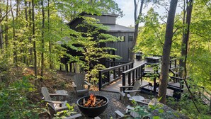 A cabin with a deck, surrounded by trees.