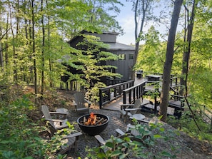A cabin with a deck, surrounded by trees.