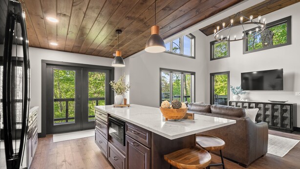 A modern kitchen with a large island, dark wooden cabinets, and a built-in oven.