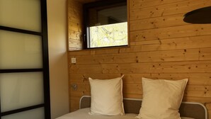 A bedroom with a wooden wall, a window, and a bed with two pillows. - La Petite Cabane (Saint-Affrique)