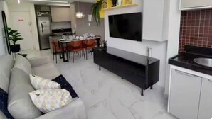 Un salon moderne avec un canapé, un téléviseur et un coin repas.