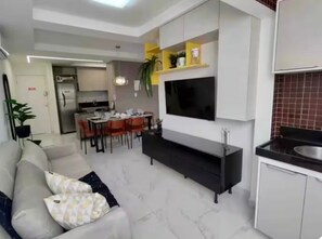 Ein modernes Wohnzimmer mit Sofa, Fernseher und Essbereich.