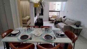 Un coin repas avec une table dressée pour quatre personnes, un canapé et une petite table d’appoint.