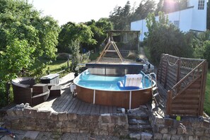 A backyard with a hot tub, a wooden deck, and a stone wall. - Apartment 'Carlo' with Private Pool, Shared Terrace and Wi-Fi (Bindlach)