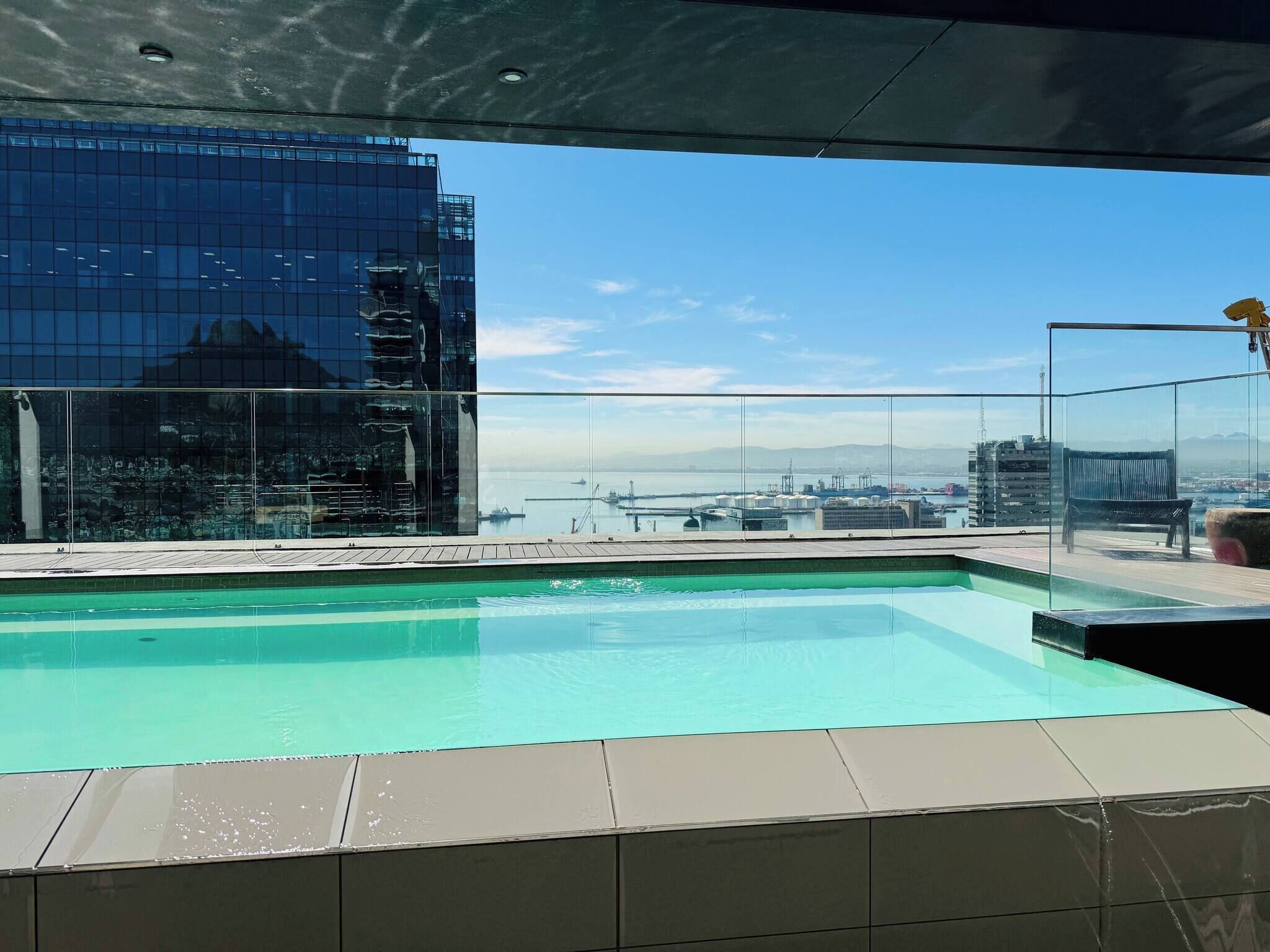 A rooftop pool with a clear view of a cityscape and a body of water.