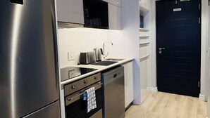 A modern kitchen with stainless steel appliances, a black door, and a light wood floor. - Cape Town Studio 16 on Bree (Cape Town)