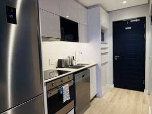 A modern kitchen with stainless steel appliances, a black door, and a light wood floor. - Cape Town Studio 16 on Bree (Cape Town)
