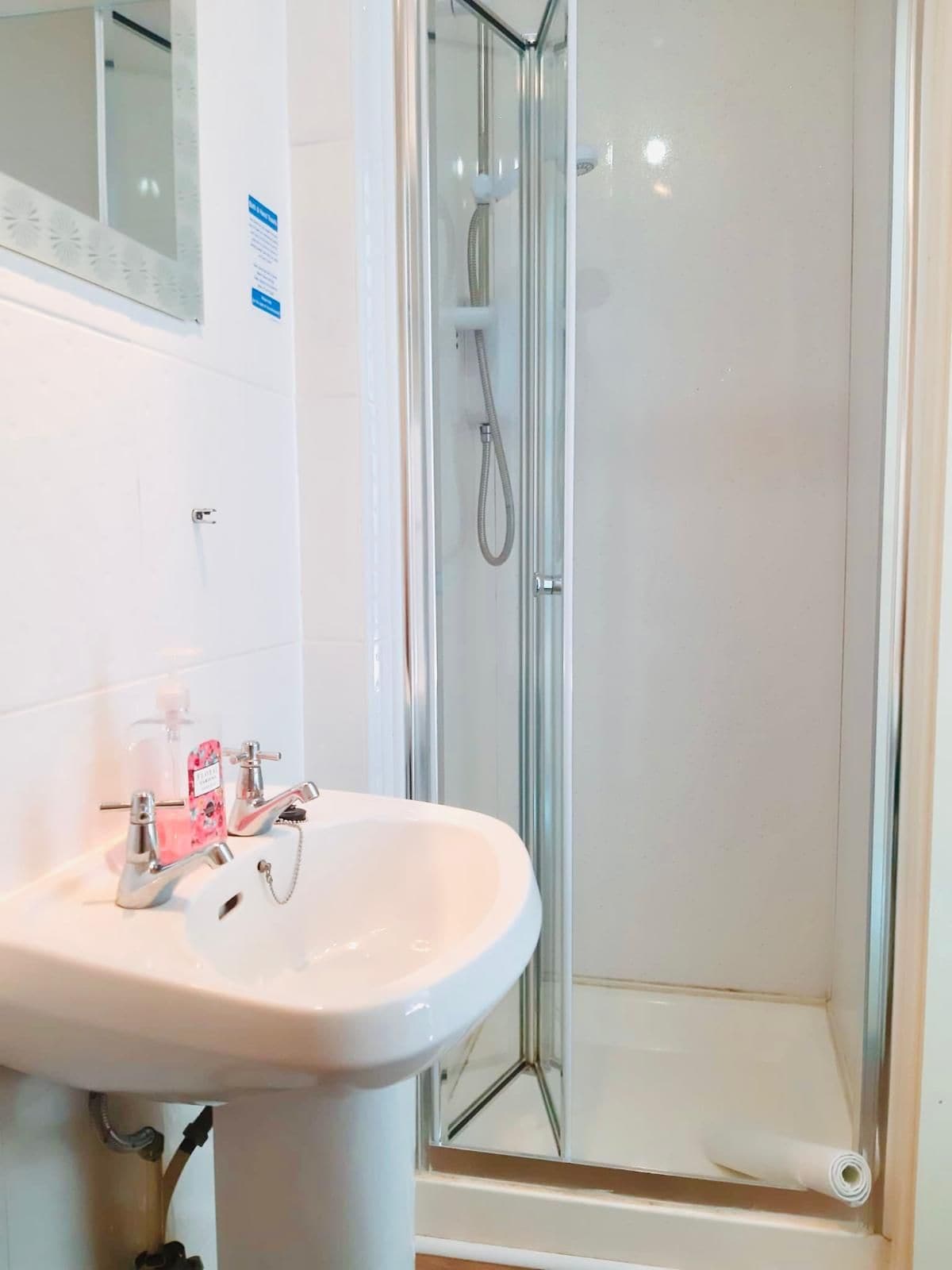 A bathroom with a white sink, a glass shower enclosure, and a mirror above the sink.