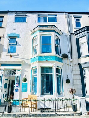 A corner building with a blue and white facade, a sign reading 'Beeches,' and a bench outside. - The Beeches Hotel (Blackpool)