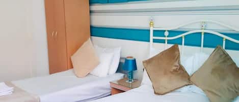 A hotel room with a bed, a wardrobe, a nightstand, and a wall with decorative floral patterns.