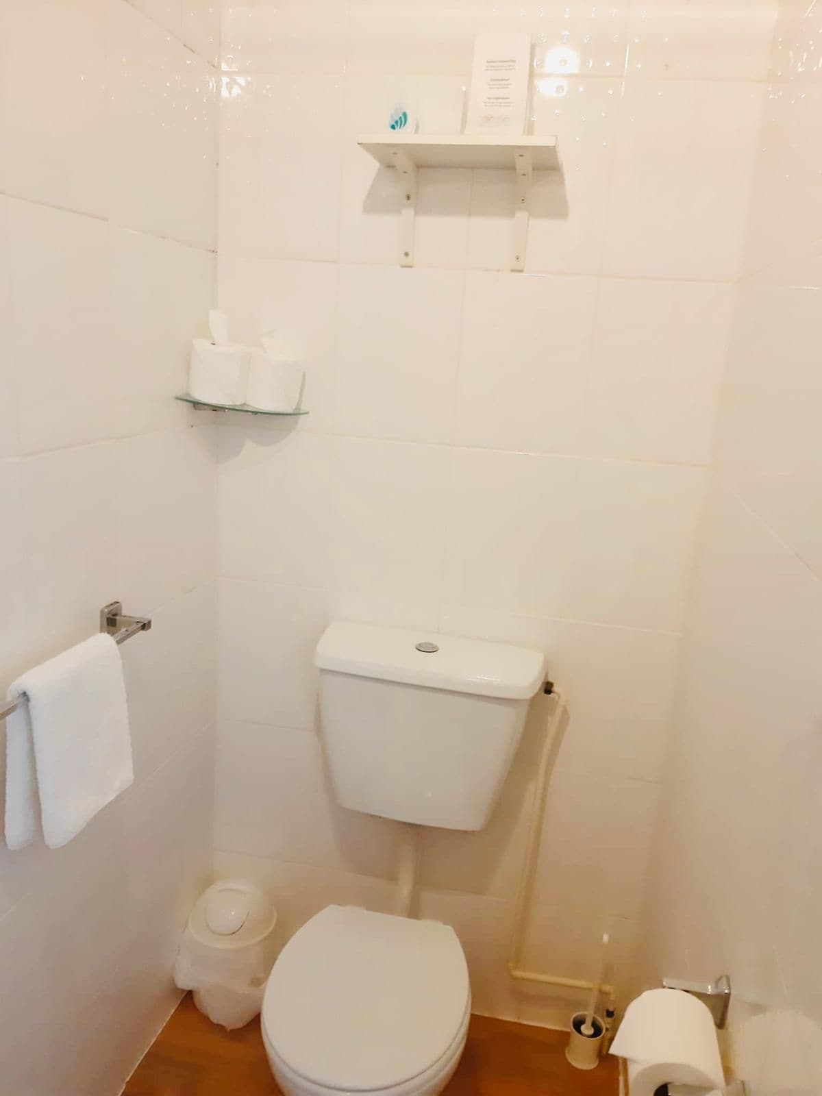 Un baño pequeño y limpio con inodoro, lavamanos y un perchero para toallas.