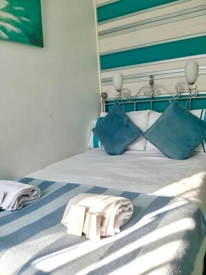 A bed with a striped bedspread, two pillows, and a folded towel on a white mattress. - The Beeches Hotel (Blackpool)