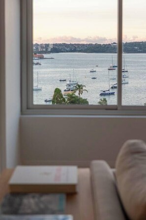 Ein Fenster mit Blick auf einen Hafen, eine Couch und einige Bücher.