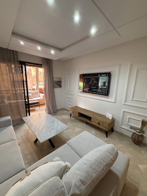 Ein modernes Wohnzimmer mit einer Couch, einem Couchtisch, einem an der Wand befestigten Fernseher und einem Holztisch.