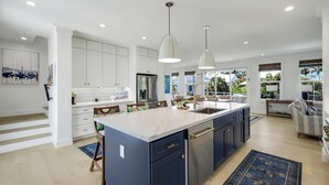A modern kitchen with a large island, white cabinets, and pendant lighting. - Cabana Blu- Luxury Captiva Home with Pool and Steps to the Beach! (Captiva)