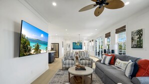 A spacious living room with a large flat-screen TV, a ceiling fan, and a sofa with decorative pillows. - Cabana Blu- Luxury Captiva Home with Pool and Steps to the Beach! (Captiva)