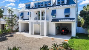 A two-story house with a covered garage, a front porch, and a driveway. - Cabana Blu- Luxury Captiva Home with Pool and Steps to the Beach! (Captiva)