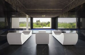 Un interno moderno con un’area salotto, ampie finestre e vista sul verde.