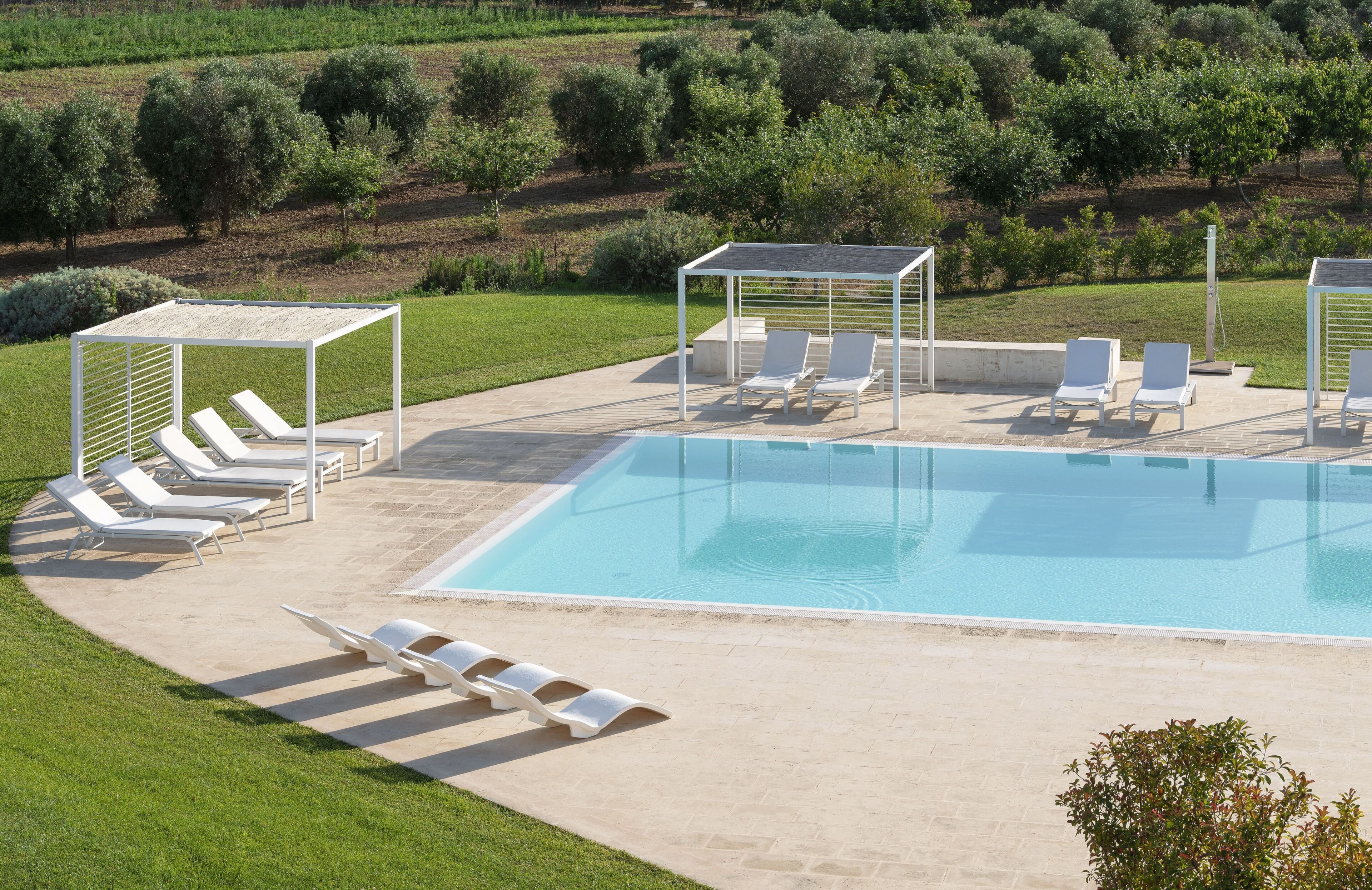 A swimming pool with lounge chairs and a pergola.