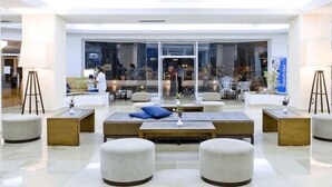 Un vestíbulo moderno con una zona de estar central, paredes de vidrio y vistas al interior.