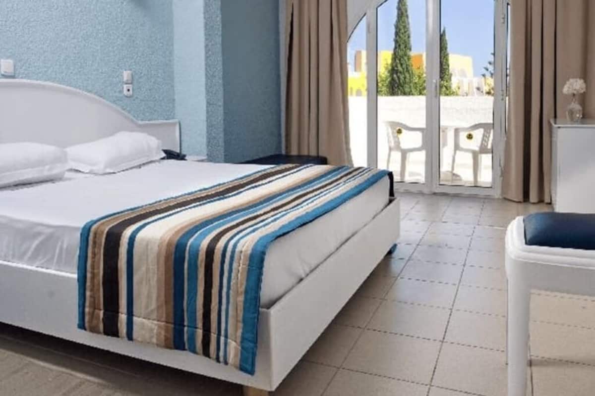 Una habitación de hotel con una cama, una ventana con cortinas y vistas al exterior.