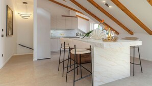 Eine moderne Küche mit Marmorarbeitsplatten, Holzbalken und einer Bar mit Hockern.