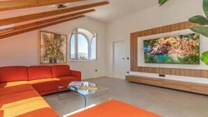 Ein modernes Wohnzimmer mit einem roten Sofa, einem Glastisch und einem großen Fernseher, der an der Wand angebracht ist.