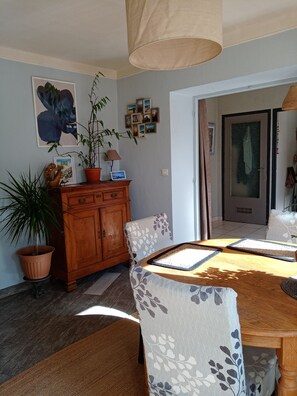 A dining area with a wooden table, chairs, a cabinet, and a potted plant. - HAMLET HOUSE in the heart of the mountains (Breil-sur-Roya)