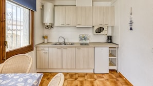 A compact kitchen with light wood cabinets, a microwave, a sink, and a coffee maker. - 'Bahia Studio' Apartment with Lake Views, Wi-Fi, and Air Conditioning (Empuriabrava)