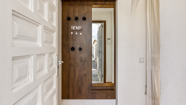 A wooden door with a 'HOME' sign and heart decorations, a white garage door, and a hallway leading to a residential street. - 'Bahia Studio' Apartment with Lake Views, Wi-Fi, and Air Conditioning (Empuriabrava)