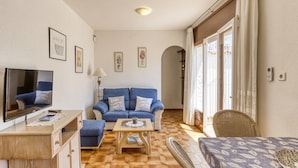 A living room with a sofa, a coffee table, a TV, and a dining area with a table and chairs. - 'Bahia Studio' Apartment with Lake Views, Wi-Fi, and Air Conditioning (Empuriabrava)