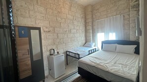 Un dormitorio con una cama, una cama individual, un armario, un escritorio y un radiador.