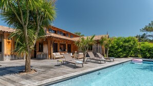 A wooden villa with a pool, lounge chairs, and a patio area. - Villa Yucca - Cap Ferret *Heated pool *Market *Beaches (Lège-Cap-Ferret)