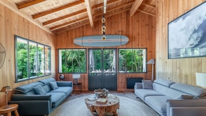 A spacious living room with a high ceiling, large windows, and a central wooden coffee table. - Villa Yucca - Cap Ferret *Heated pool *Market *Beaches (Lège-Cap-Ferret)