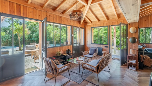 A spacious wooden interior with large windows, a dining area, and a seating area. - Villa Yucca - Cap Ferret *Heated pool *Market *Beaches (Lège-Cap-Ferret)