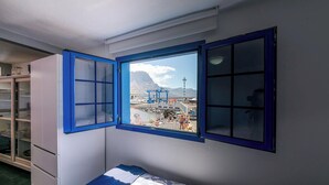 Ein Zimmer mit großem Fenster, einem Bett und einem weißen Schrank.