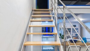 Eine moderne Treppe mit Holzdielen und Metallgeländern führt zu einem Küchenbereich mit blauer Beleuchtung.