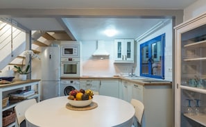 Une cuisine moderne avec un coin repas, des appareils électroménagers intégrés et un escalier.