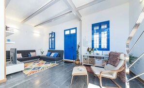 Un salon moderne avec un canapé, un fauteuil et un téléviseur.