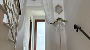 Een trap met witte gordijnen, een decoratieve spiegel en een vloerlamp.